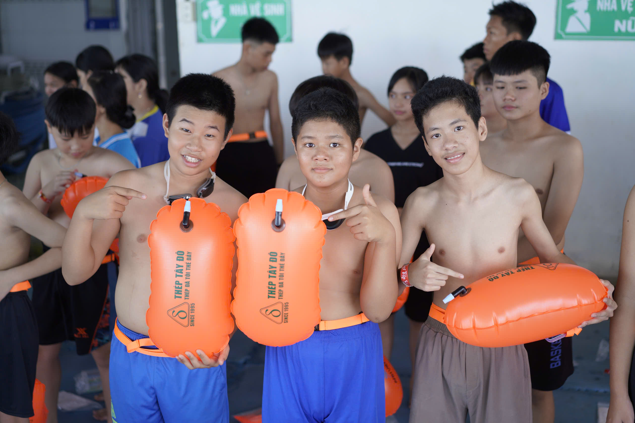 A group of boys holding orange floaties  AI-generated content may be incorrect.